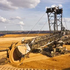 Giant bucket wheel excavator Excavator is taking away the layers of ground before digging the brown coal. Largest open pit lignite mine in Europe. Power stations at horizon transform the coal to electricity.