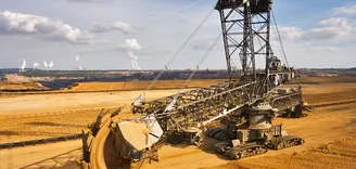 Giant bucket wheel excavator Excavator is taking away the layers of ground before digging the brown coal. Largest open pit lignite mine in Europe. Power stations at horizon transform the coal to electricity.
