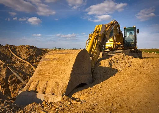 Dirty yellow excavator in a sunny summer day