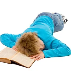 Tired teenager boy fallen asleep on his book